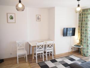 a living room with a table and chairs and a tv at Apartament Mrągowska - Żabi Staw in Mikołajki