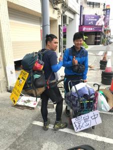 Zwei Männer stehen neben einem Gepäckwagen. in der Unterkunft 履舍民宿Footinn in Taitung