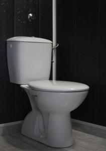 a white toilet in a bathroom with black walls at Guest House Dar in Tryavna