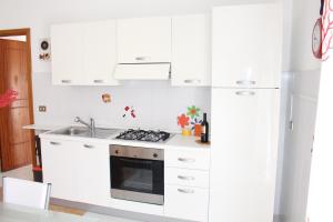 uma cozinha branca com um fogão e um lavatório em La Fata em Balestrate