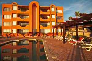 un hôtel avec une piscine, des chaises et un bâtiment dans l'établissement Sunrock Hotel & Suites, à Cabo San Lucas