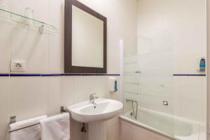 a white bathroom with a sink and a mirror at Hotel Patio de las Cruces in Seville
