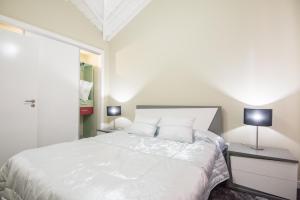 a bedroom with a large white bed with two lamps at Casa Céu D'Abraão in Piedade