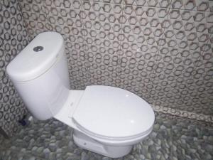 a white toilet in a bathroom with a stone wall at Sawe Homestay in Kuta Lombok