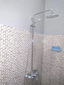 um chuveiro na casa de banho com uma parede de azulejos em Sawe Homestay em Kuta