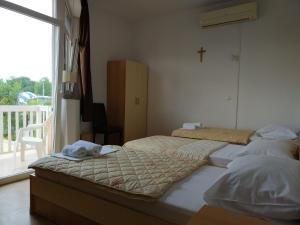 two beds in a room with a cross on the wall at Guest House Regina Mundi in Međugorje