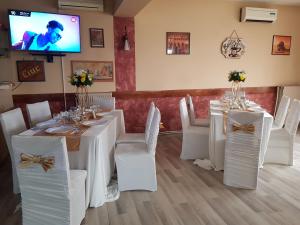 jadalnia z białymi stołami i krzesłami oraz telewizorem w obiekcie Mon Cheri w mieście Drobeta-Turnu Severin