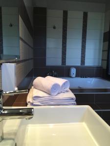 a bathroom with a sink and a tub and towels at Maison Hotel in Halkidona