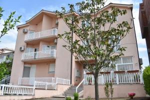 un edificio de apartamentos de color rosa con balcones blancos y un árbol en Guest House Regina Mundi, en Međugorje