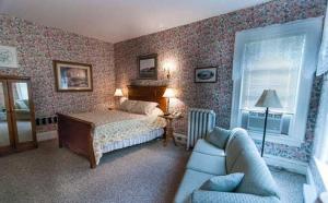 1 dormitorio con 1 cama y 1 sofá en Carriage House Inn, en Fredericton