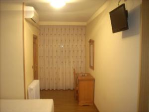Habitación con dormitorio y TV en la pared. en Hotel Corona de Castilla, en Villares de la Reina