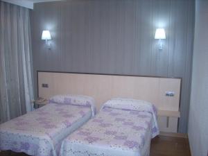 1 dormitorio con 2 camas y 2 luces en la pared en Hotel Corona de Castilla, en Villares de la Reina