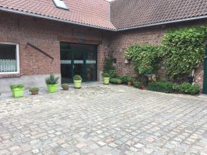 un bâtiment en briques avec une cour ornée de plantes en pot dans l'établissement Ferme BROCART, à Bouvines