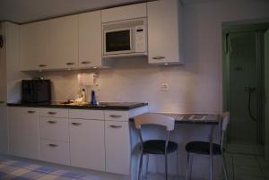 インターラーケンにあるApartment Riverholidayのキッチン(白いキャビネット、テーブル、椅子付)