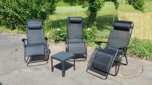 three chairs and a table in front of a yard at Le petit Husseau in Montlouis-sur-Loire