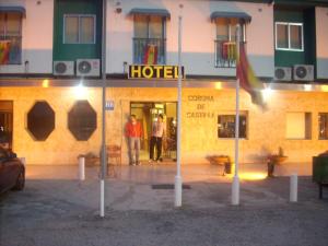 Hotel Corona de Castilla في Villares de la Reina: شخصين واقفين خارج الفندق في الليل