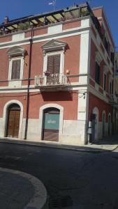 een rood-wit gebouw met een balkon in een straat bij Antico Molino in Trani