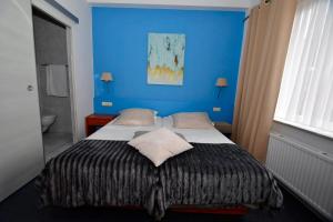 a bedroom with a bed with a blue wall at Hotel 'T Hert in Genk
