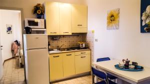 una cucina con armadi gialli e frigorifero bianco di Condominio Moschettieri trilocale a Bibione