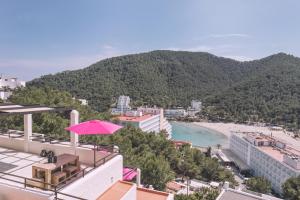 uma vista para a praia a partir de um edifício com um guarda-sol em Apartamentos Catharina Maria em Cala Llonga