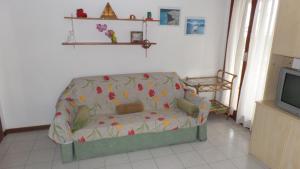 a living room with a couch and a tv at Appartamenti LUNGOMARE SABBIADORO in Lignano Sabbiadoro