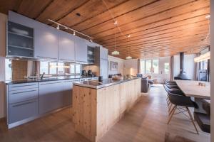 ヴェンゲンにあるSchweizerheim Residence 11の白いキャビネットと木製の天井が備わるキッチン