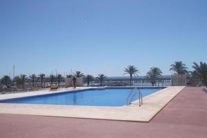een groot zwembad met palmbomen en de oceaan bij Luxury private apartment at the beach in a 4 star hotel first beach line in Fuengirola