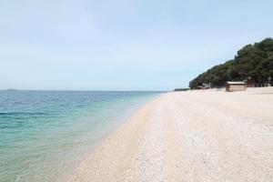 une plage de sable avec l'océan en arrière-plan dans l'établissement Apartments Maras, à Primošten