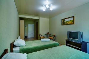 a hotel room with two beds and a tv at Domashniy in Kamianets-Podilskyi