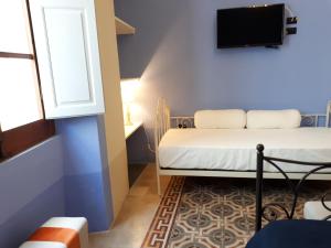 um pequeno quarto com uma cama e uma televisão em Residenza Sofia Pandora em Carloforte