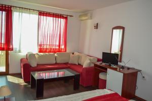 a living room with a red couch and a tv at Hotel Romantika in Varna City