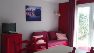 PloemelにあるLes Cottages Du Golf De Saint Laurentのリビングルーム(赤いソファ、テーブル付)
