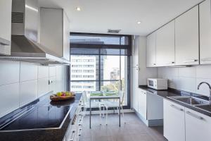 een keuken met witte kasten en een tafel en stoelen bij The Lonely Chimney Apartments in Barcelona
