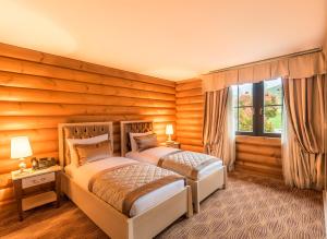 two beds in a bedroom with wooden walls at Quba Palace Hotel & Golf Resort in Quba