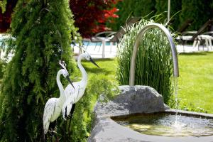 Dos pájaros blancos están parados junto a una fuente. en Pension Sattlerenglhof, en Laces