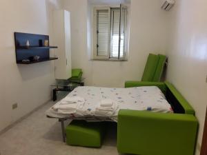 パキーノにあるCasa Francescoのベッド1台と緑の椅子2脚が備わる小さな客室です。