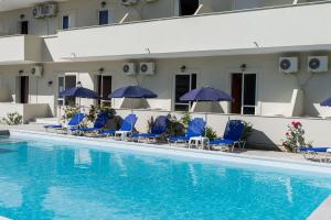 a hotel swimming pool with blue chairs and umbrellas at Laganas Dreams 2 in Laganas