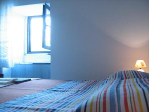 ein Schlafzimmer mit einem Bett mit einer gestreiften Decke und einem Fenster in der Unterkunft Podmartine in Baška