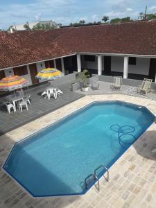 a large blue swimming pool with chairs and umbrellas at Pousada Por do Sol in Cananéia