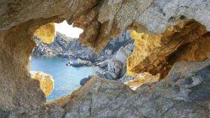 a rock cave with a view of a body of water at B&B Sa Pintadera in Muravera