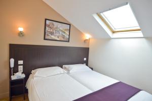 a bedroom with two white beds and a skylight at Hôtel du Quai de Seine in Paris