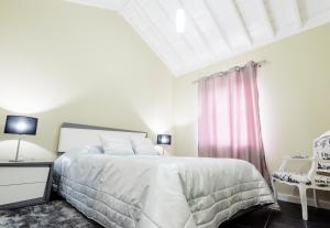 a white bedroom with a bed and a window at Casa Céu D'Abraão in Piedade