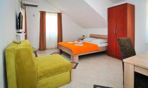 a bedroom with a bed and a yellow chair at Apartmani Bekonja in Tivat