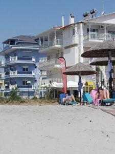 un gruppo di persone seduti sulla spiaggia vicino a un hotel di Milla Lux 1 a Paralia Katerinis