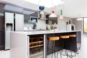 ロンドンにあるVeeve - Bespoke Wimbledon Retreatのキッチン(白黒のキャビネット、スツール付)