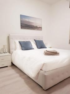 een wit bed met blauwe kussens in een witte slaapkamer bij Fabulous view on the Lake in Valsolda