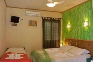 a bedroom with two beds and a green wall at Pousada Praia do Curral in Ilhabela