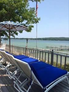 Churchill Pointe Inn في Hubbard Lake: كرسي الصالة ومظلة على الشاطئ