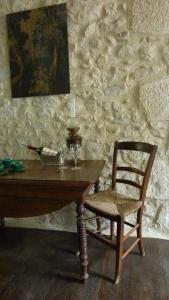 a wooden table and a chair with a wine glass at Le Logis Alexandra BnB in La Trimouille