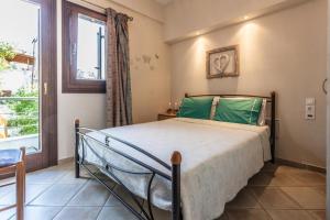a bedroom with a bed with green pillows and a window at Rena's House Afissos in Afissos